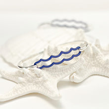 Load image into Gallery viewer, the beach and back double wave tension closure bangle in marine blue enamel with silver bangle set upon white sea stars on white background
