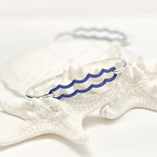 Load image into Gallery viewer, the beach and back double wave tension closure bangle in marine blue enamel with silver bangle set upon white sea stars on white background