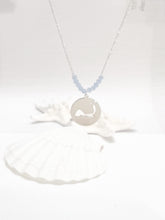 Load image into Gallery viewer, the beach and back cape cod necklace in silver with pale blue beads at center of chain and coin shape pendant with cutout silhouette of cape cod pictured in front of white seashells on white background
