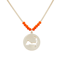 Load image into Gallery viewer, the beach and back cape cod necklace in gold with coral beads at center of chain and coin shape pendant with cutout silhouette of cape cod