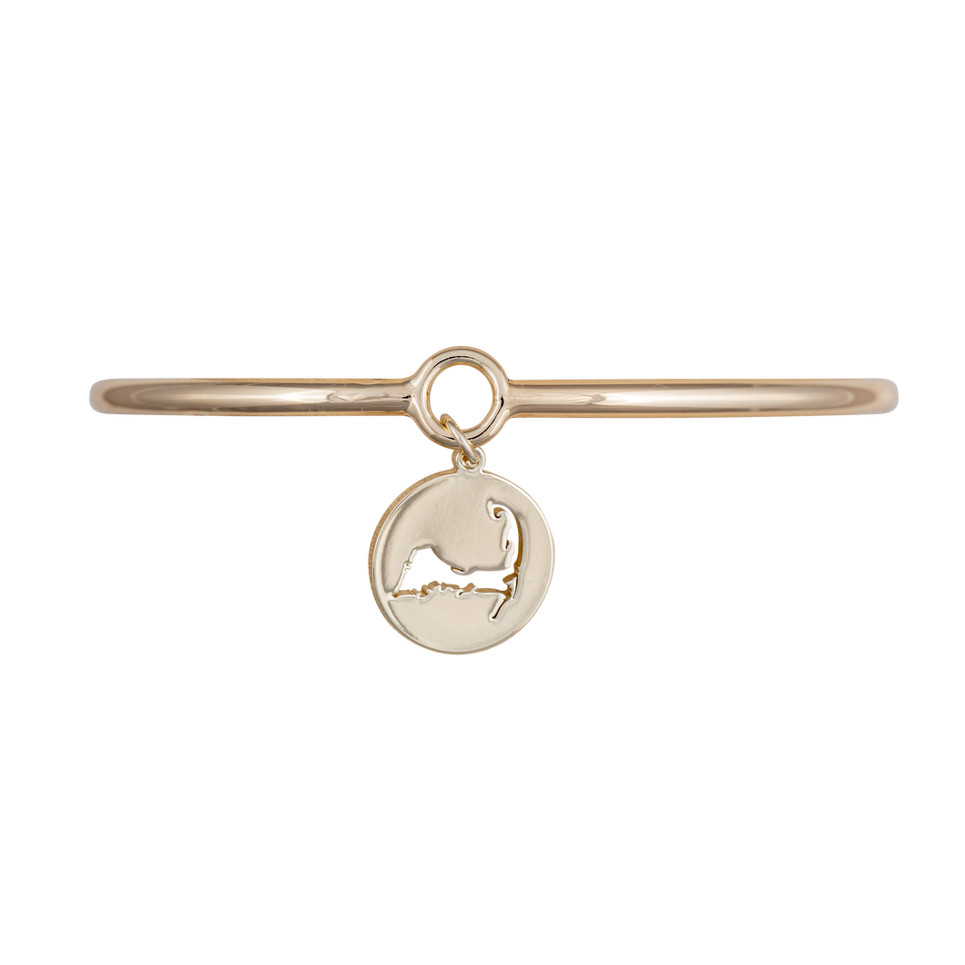 Gold bangle featuring a coin charm with a Cape Cod cutout. The charm adds coastal elegance to the accessory