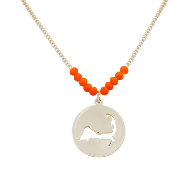 the beach and back cape cod necklace in gold with coral beads at center of chain and coin shape pendant with cutout silhouette of cape cod