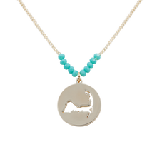 Load image into Gallery viewer, the beach and back cape cod necklace in gold with turquoise beads at center of chain and coin shape pendant with cutout silhouette of cape cod
