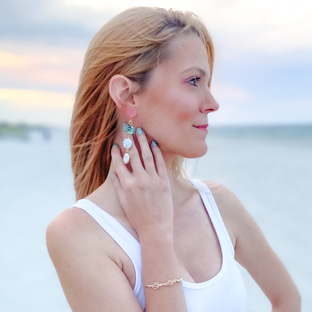 ocean springs triple abalone and coin pearl linear earrings on model on beach at sunset