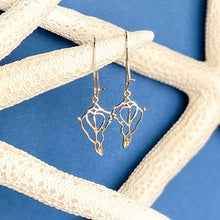 Load image into Gallery viewer, the beach and back single drop gold conch shell earrings on loop wire hanging from white sea stars on blue background
