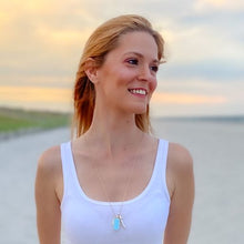 Load image into Gallery viewer, mantoloking charm necklace in blue opal on model wearing white tank top on beach
