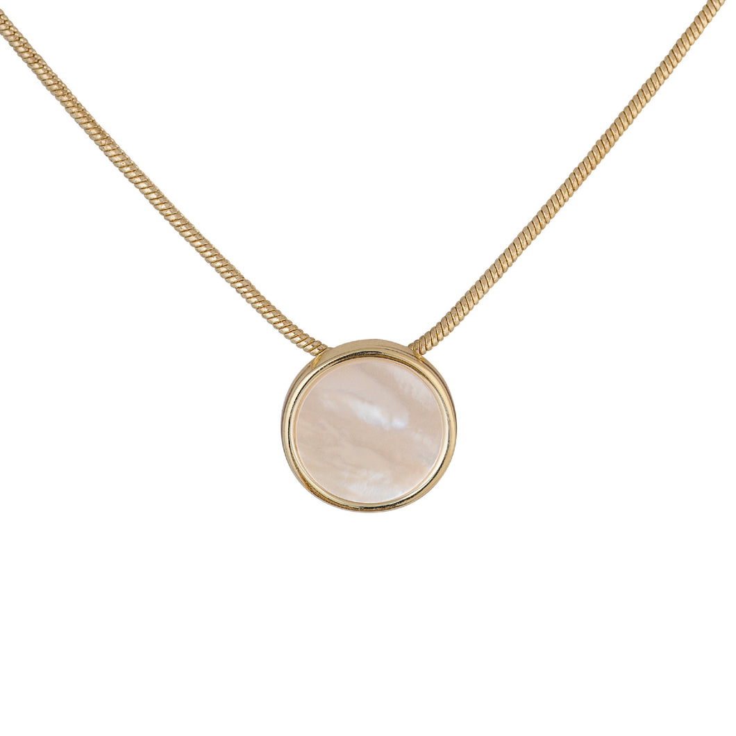 a small circular pendant with a gold bezel set shimmering, iridescent mother-of-pearl center. The pendant hangs from a gold-plated brass snake chain. and has a white background.